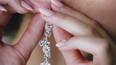 woman-with-manicure-puts-on-earring-with-gems-closeup