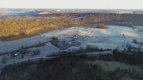 aerial landscape of frozen farmland covered in frost with sun setting over the forest and river