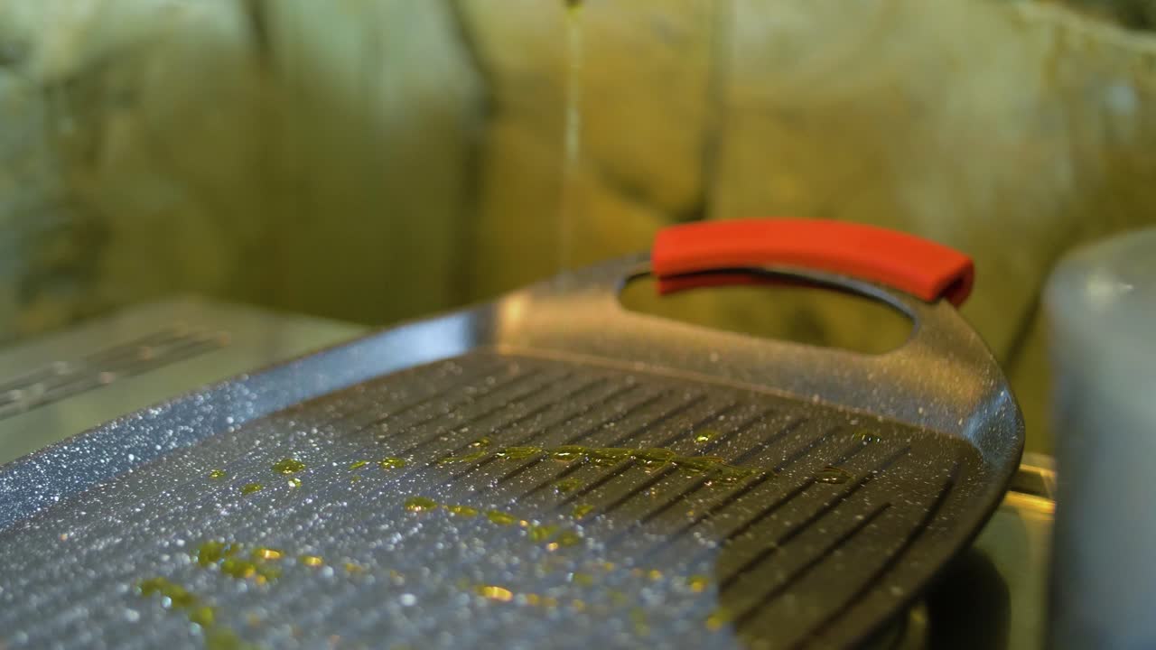 Slowmotion af olivenolie, der hældes på en stegepande.