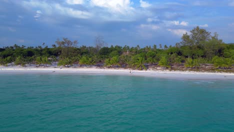 tourist walking on the white sand beach of koh rong island in cambodia, asia. tremendous aerial view flight fly push forward drone