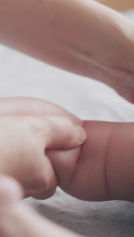 skilled pediatrician holds newborn baby small leg and practices massage actively on changing table close view