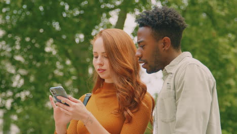 Pareja-Joven-Viajando-Juntos-Por-La-Ciudad-Siguiendo-Instrucciones-En-La-Aplicación-De-Mapas-En-El-Teléfono-Móvil