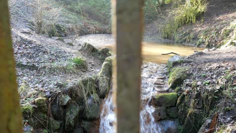 small cascading rock waterfall copper coloured pool flowing behind metal railings closeup dolly right