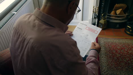a lonely senior man opening a debt letter