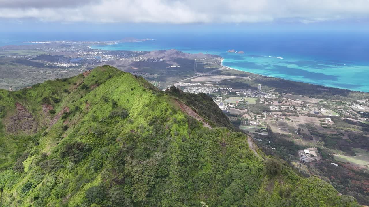 Drone flying above the high mountain peaks on Oahu, Hawaii, revealing blue ocean sea water and coastline in cinematic aerial footage