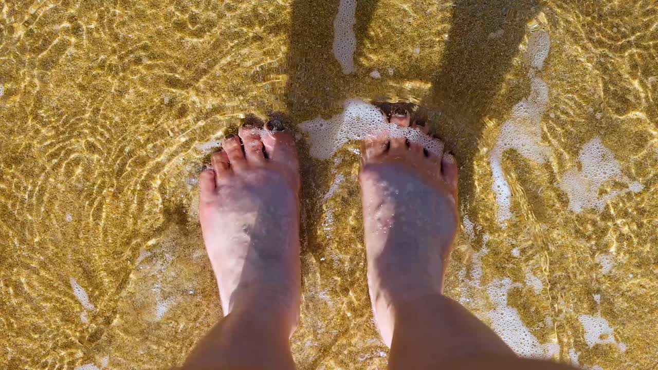 pies disfrutando de las olas en una playa de arena