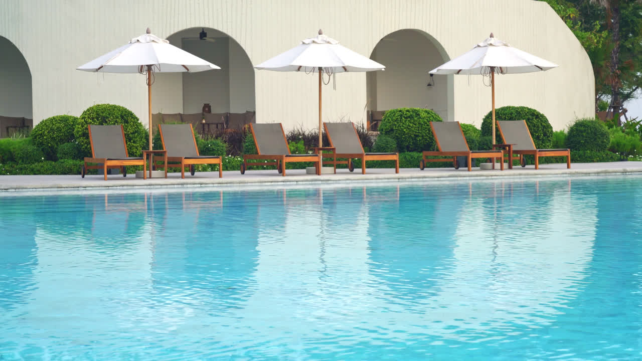 Paraply med seng pool omkring swimmingpool med hav hav baggrund - ferie og ferie koncept
