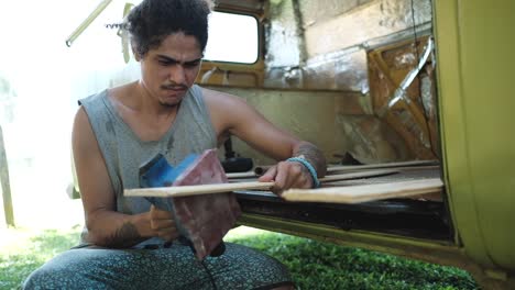 craftsman polishing wooden plank near carava