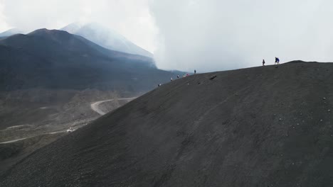 tourist people hiking on crater of mount etna volcano in sicily, italy - aerial 4k