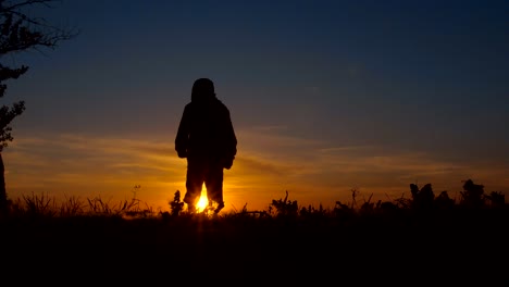 silhouette of a boy playing at sunset near a lake