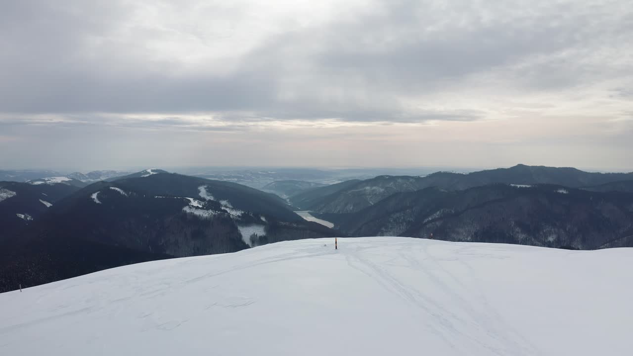 Solitary figure on Gainatu Peak with Rausor Dam in background, Iezer-Papusa Mountains, Arges, Romania, winter scene