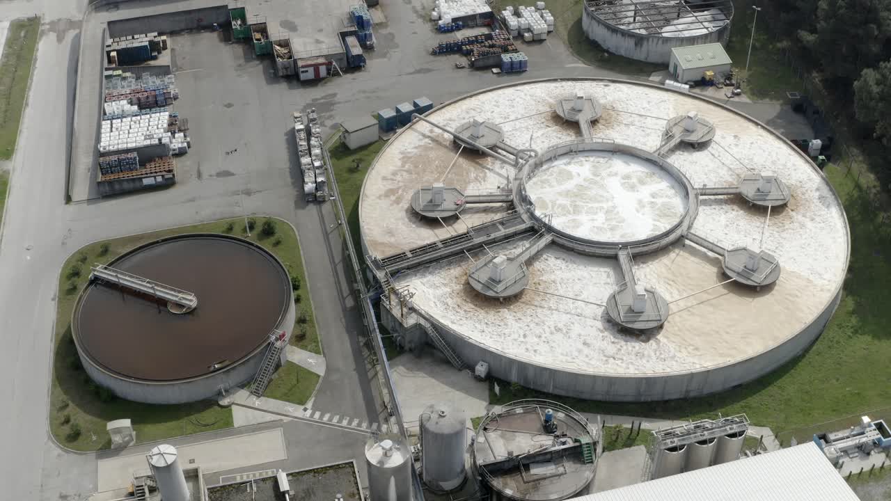 Aerial circling large circular water treatment or settling tanks at DRT industrial factory complex, Veille-Saint-Girons, France