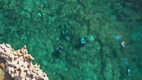 drone shot pulling up away from divers in crystal clear seas in cirkewwa malta