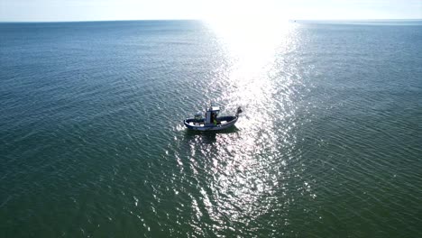 Lone-boat-drags-lines-through-open-ocean-as-it-is-towed,-aerial-orbit