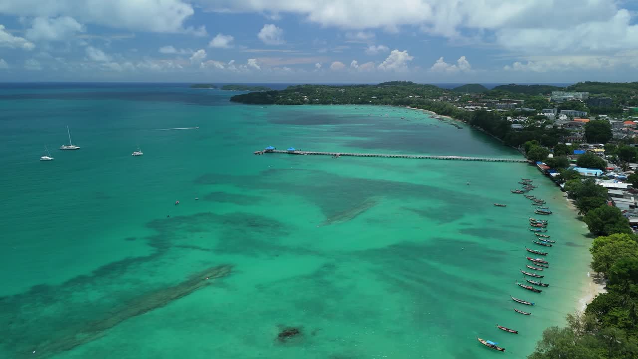 Drone flies right past Rawai Beach as clouds drift over clear turquoise water