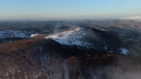 Low-clouds-above-mountainous-landscape-in-winter-with-snowy-forests