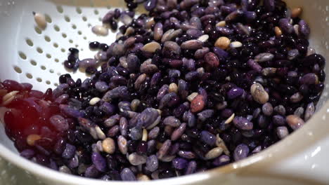 closeup detail of wet purple black beans in white colander