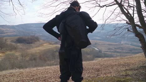 man equipping black tactical armor, stands on the edge of a hill with arms outstretched, surveying the vast valley below. his presence exudes power, strategy, and readiness for the mission ahead