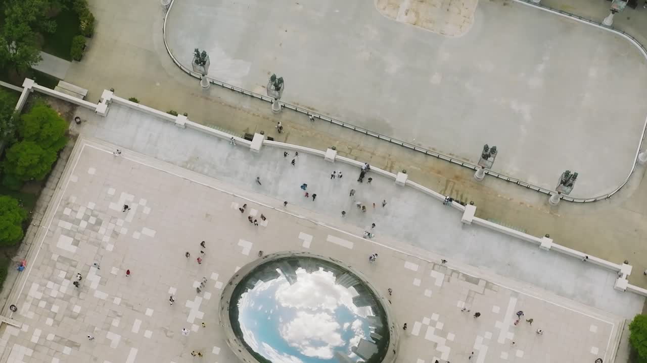 People walk around an outdoor area in Chicago near a reflective sculpture