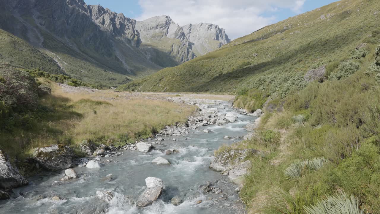 río azul que corre por un valle entre montañas en un soleado día de verano en rees dart track, nueva zelanda