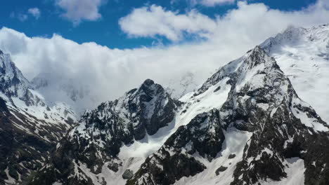 vuelo aéreo a través de nubes montañosas sobre hermosos picos nevados de montañas y glaciares.