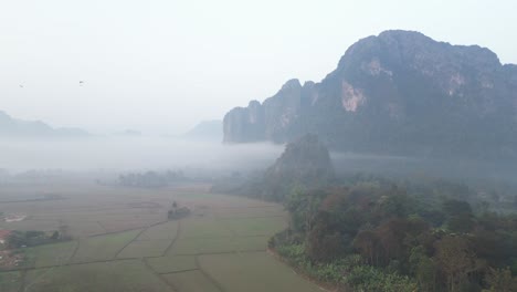 Toma-De-Drones-De-Niebla-Que-Llena-El-Valle-En-Vang-Vieng,-La-Capital-De-Aventuras-De-Laos.