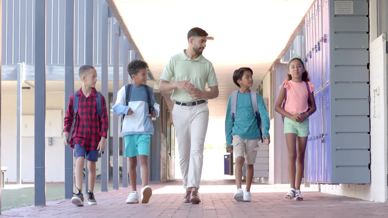 Walking down school hallway, teacher and students with backpacks
