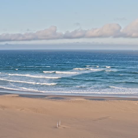 aerial drone view of waves breaking onto sandy beach shore