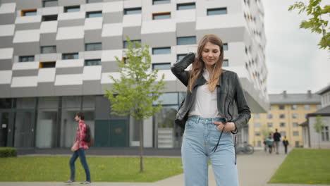 stylishly dressed girl having fun outdoors in jeans clothes and leather jacket looks happy and