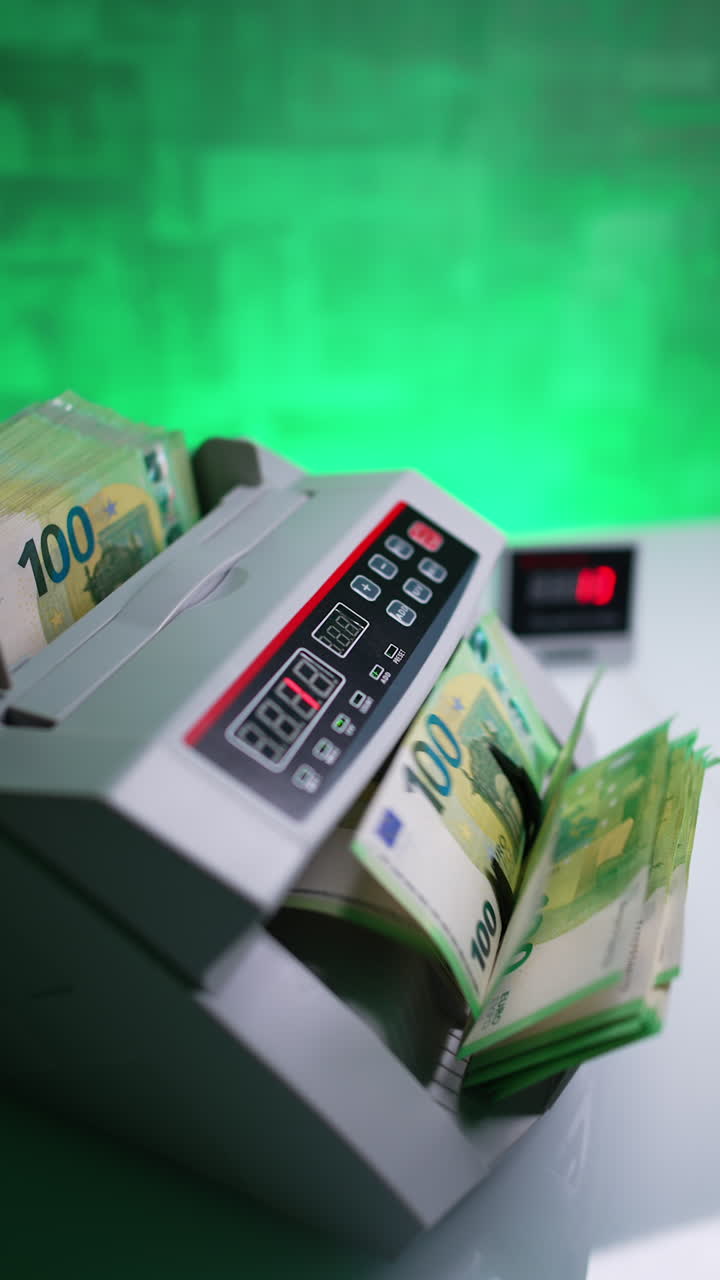 Woman puts one hundred euro stack to a money counting machine. Side view of the equipment working in the bank. Vertical video.