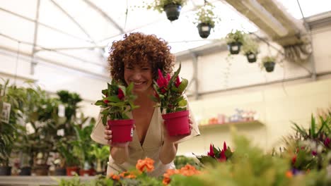 happy young female holding potted plants while dancing in greenhouse
