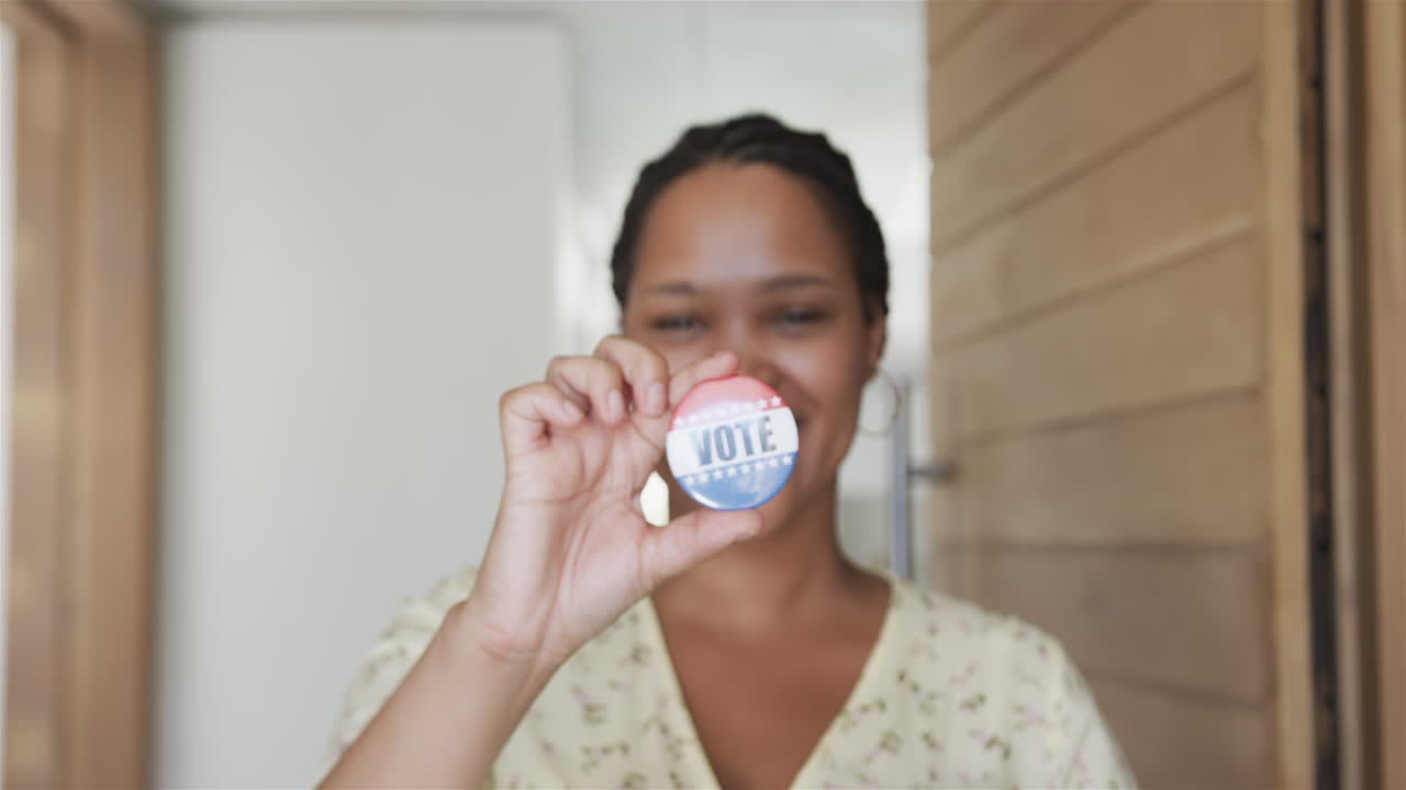 joven biracial muestra una insignia de 'voto' en casa, con espacio para copiar