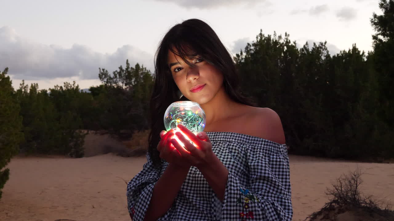 A gorgeous woman sorceress wandering in a fantasy landscape with a magical spiritual orb glowing in illuminated light.