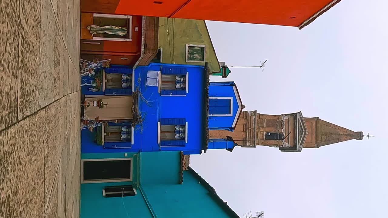 superficie del suelo de ángulo bajo fpv pov hacia casas coloridas y campanario inclinado de burano en italia