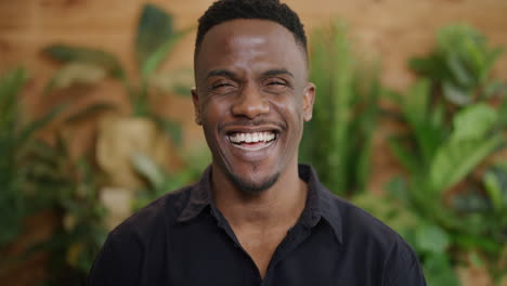 retrato de un joven afroamericano atractivo sonriendo emocionado disfrutando de un estilo de vida exitoso con camisa negra en cámara lenta