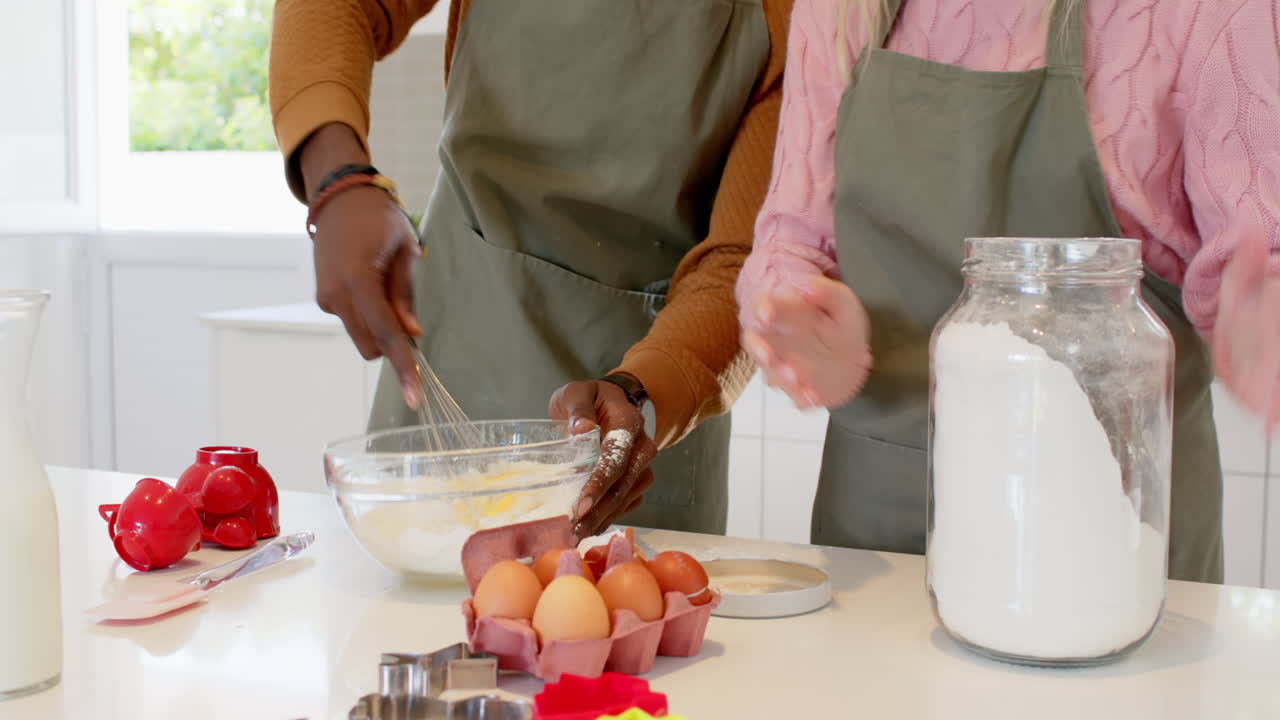 diverse couple baking together in kitchen, mixing ingredients with joy
