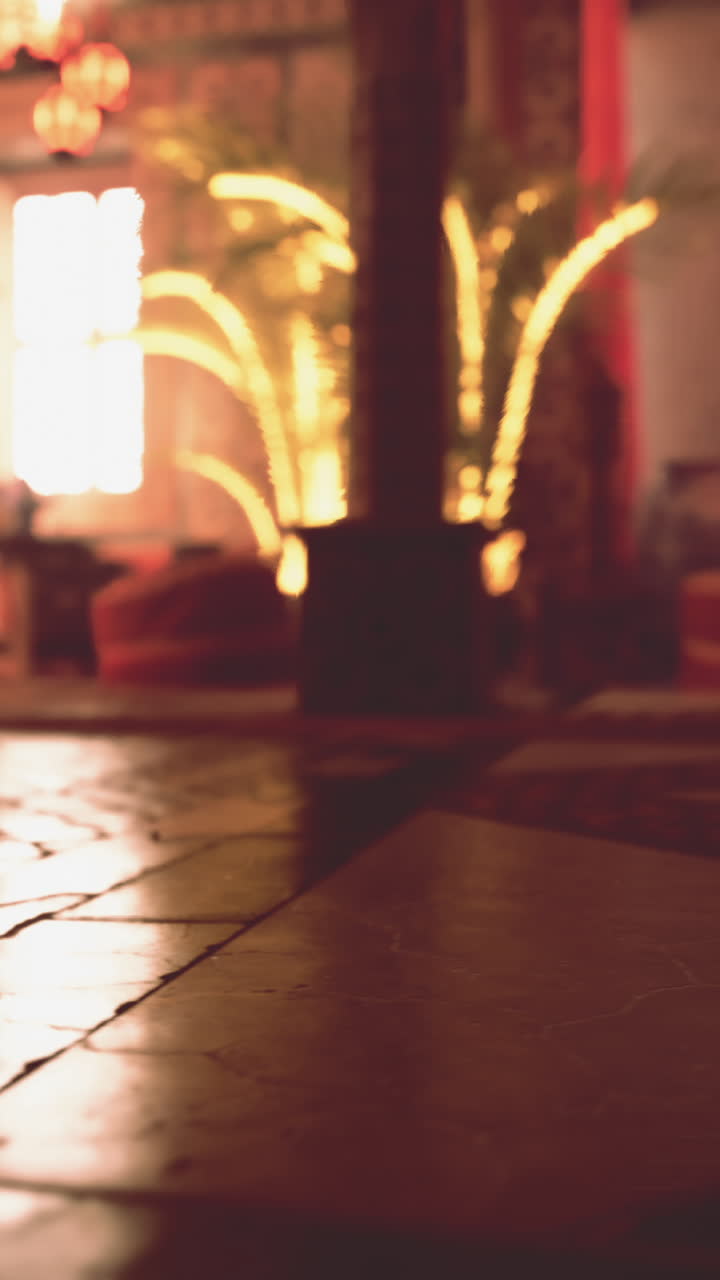 un interior cálido y acogedor con un piso de madera y azulejos, una ventana con iluminación cálida, una planta y muebles.