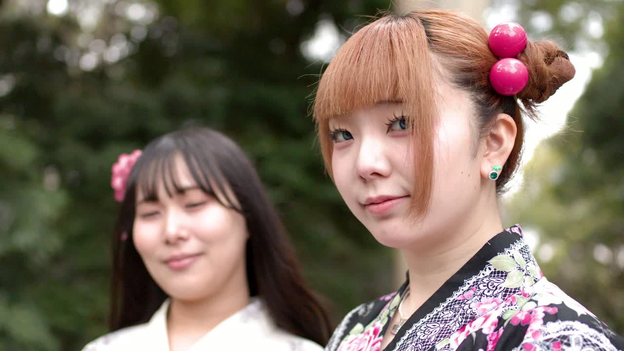 Ritratto ravvicinato di due giovani donne giapponesi che indossano kimono tradizionali in un santuario shintoista.