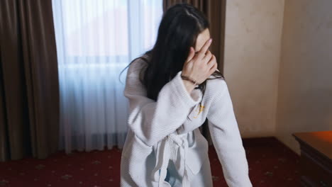 woman unpacking luggage in hotel. disappointed woman in white dressing gown looking at someone else's clothes in the suitcase.