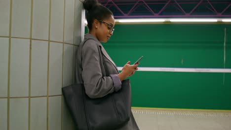 mujer usando el teléfono en una estación de metro