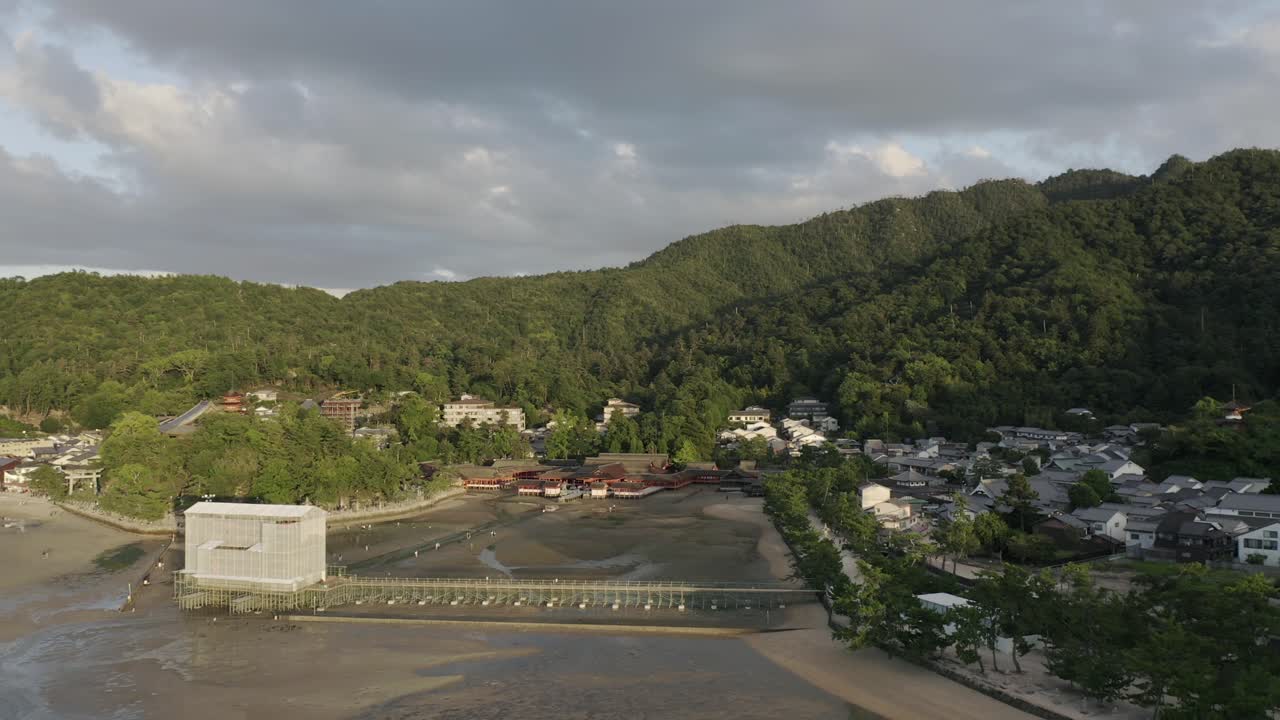 A drone pull back shot at sunset of Itsukushima Shrine being renovated in Miyajima Island, Hiroshima, Japan