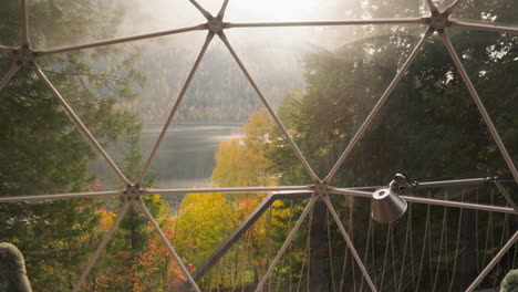 lake view from glass balcony at glamping house. peaceful retreat to rest enjoying serene ambiance of autumn nature. glamping hotel bungalow for rent