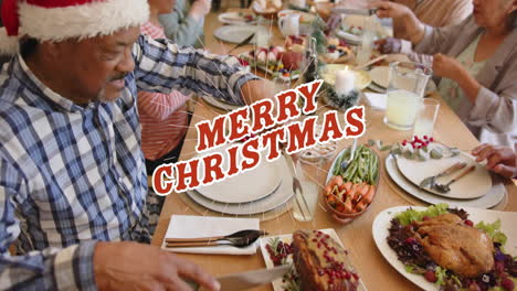 animation of merry christmas text over diverse senior friends at christmas dinner at home