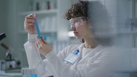 scientist examining test tube with blue liquid in medical laboratory