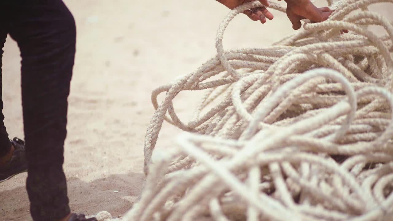 close up of unidentifiable Fisherman's hands gathering thick fishing ropes at shore