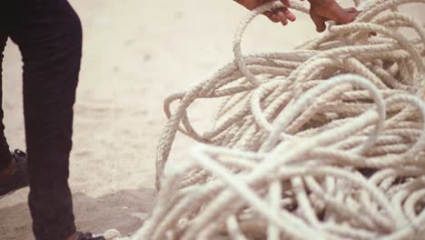 close up of unidentifiable Fisherman&#039;s hands gathering thick fishing ropes at shore