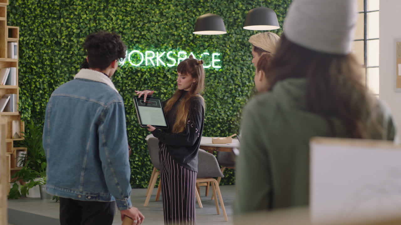 젊은 비즈니스 그룹의 백인 팀 리더 여성이 디지털 태블릿 컴퓨터를 사용하여 아이디어를 공유하고 다민족 사무실에서 스크린에서 교육 프로젝트를 보여줍니다.