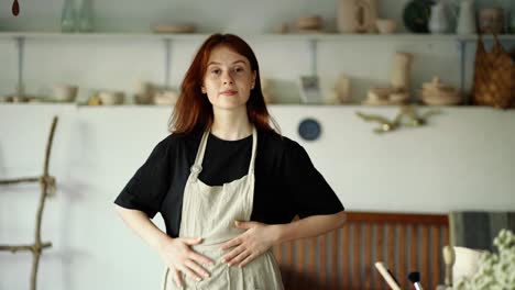 Girl-potter-wipes-her-hands-on-her-apron-and-poses