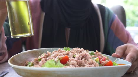 woman adding olive oil to a tuna salad