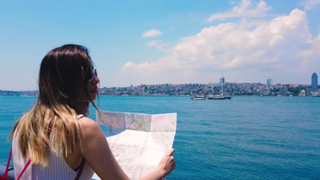 slow motion:beautiful girl looks map of istanbul with view of bosphorus,a popular destination in uskudar,istanbul,turkey